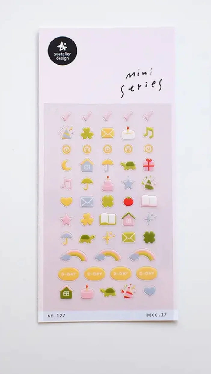 A sheet of small decorative stickers labeled 'mini series' by designer Susumu Yagi, featuring pastel icons such as hearts, stars, rainbows, envelopes, and small objects on a pale pink backing by Suatelier Design.
